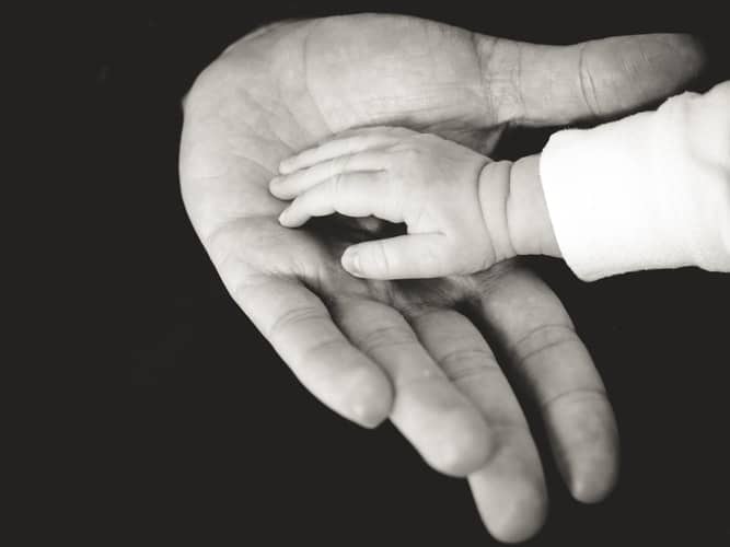 כף יד של תינוק בתוך יד מבוגר